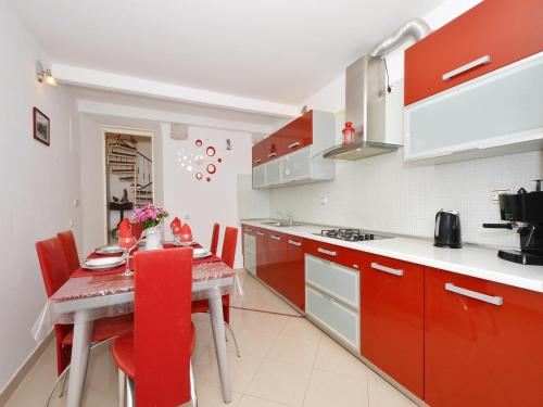 una cocina con armarios rojos y una mesa con sillas rojas en Apartment Nikolina, en Trogir