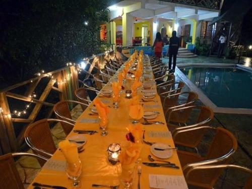 Bay View Eco Resort & Spa في بورت أنطونيو: طاولة طويلة مع الأطباق وكؤوس النبيذ بجوار حمام السباحة
