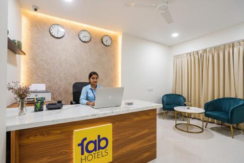 a woman sitting at a reception desk with a laptop at FabHotel Rooms 27 - Nr Hitech City in Hyderabad