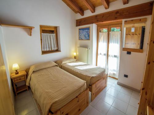 two beds in a room with a window at Alpine Bliss A Cosy Retreat in Antey-Saint-André