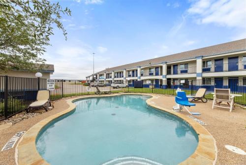 a swimming pool with chairs and a building at Days Inn by Wyndham McKinney in McKinney