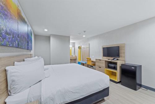 a bedroom with a white bed and a tv at Days Inn by Wyndham McKinney in McKinney
