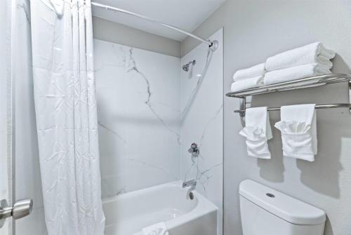 a bathroom with a shower and a toilet and towels at Days Inn by Wyndham McKinney in McKinney