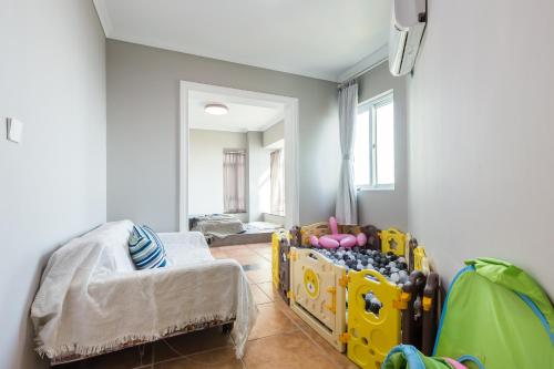 a childs room with a yellow crib and a chair at Sanya Sun Seaview Apartment in Sanya