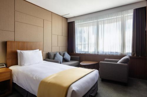 a hotel room with a bed and chairs and a window at Hotel Venue-G Seoul in Seoul