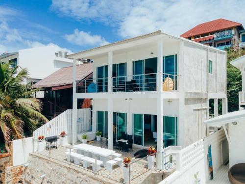 a white house with large glass windows at Phaladise Beach Villa at Phala Beach, Ban Chang in Rayong
