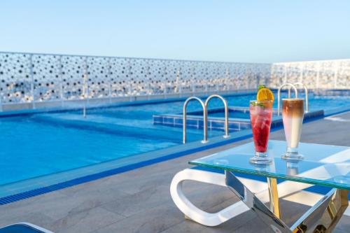 two drinks on a table next to a swimming pool at Dancenter Jeddah Near King Fahd's Fountain in Jeddah