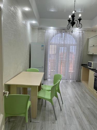 a dining room with a table and green chairs at Апарт 2 комн Гринплаза in Aktau