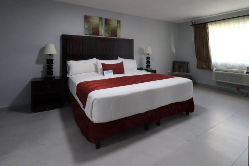 a bedroom with a large bed with a red blanket at Quality Inn Piedras Negras in Piedras Negras