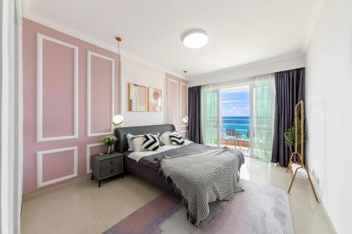 a bedroom with a bed with a view of the ocean at Sanya Sun Seaview Apartment in Sanya