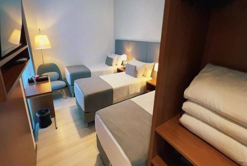 a small hotel room with two beds and a chair at Dazzler by Wyndham Ciudad del Este in Ciudad del Este