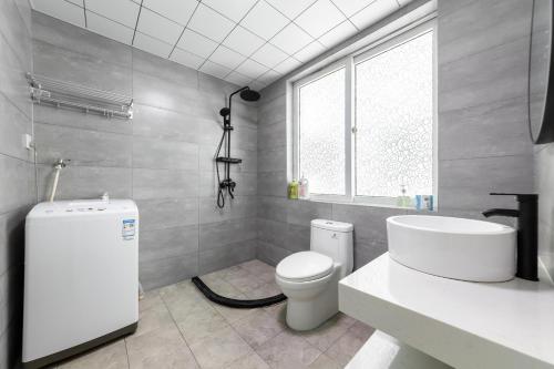 a bathroom with a toilet and a sink and a window at Sanya Sun Seaview Apartment in Sanya