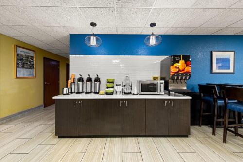 een keuken met een aanrecht met een magnetron en een aantal stoelen bij Quality Inn Warrensburg in Warrensburg