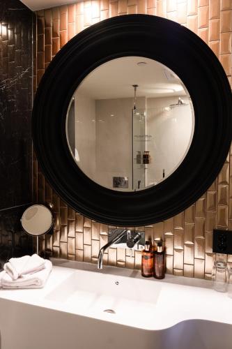 a bathroom with a large mirror above a sink at Home Hotel Havnekontoret in Bergen