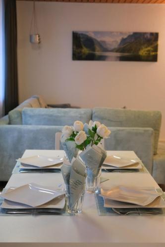 a table with plates and a vase with flowers on it at Apartment Goldey in Unterseen
