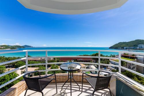 a balcony with chairs and a table and the ocean at Sanya Sun Seaview Apartment in Sanya