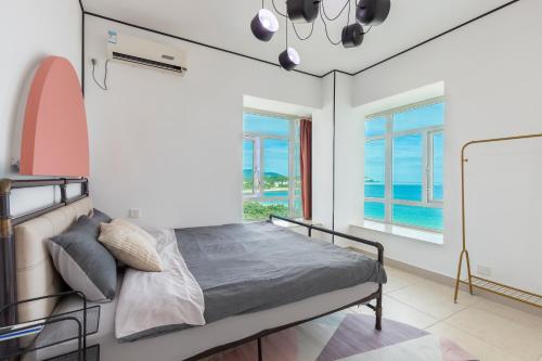 a bedroom with a bed in a room with windows at Sanya Sun Seaview Apartment in Sanya
