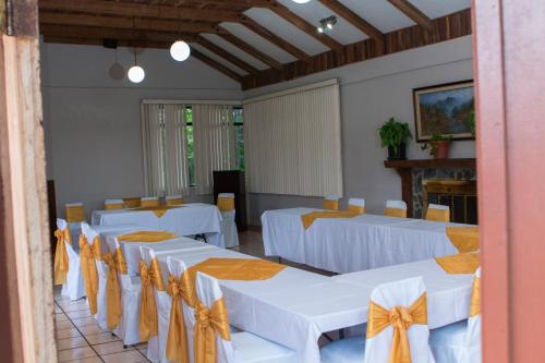 a room with white tables and chairs with orange bows at Hotel Villa Zurqui in San José