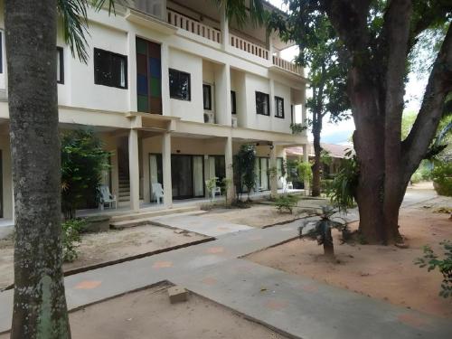 a large white building with trees in front of it at Jinta Hotel Nathon Beach in Chaweng