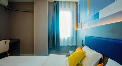 a bedroom with a bed with a blue headboard and a window at 7 Days Inn Xi'an Railway Station in Xi'an