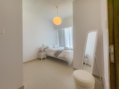 Una habitación blanca con una cama y un espejo. en Stylish 1BR Apt in Gate Tower 3, en Abu Dabi