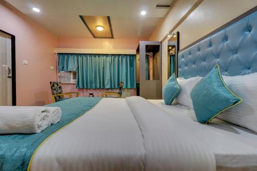 a bedroom with a large bed with a blue headboard at Hotel Platinum Inn in Navi Mumbai