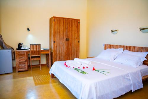 a bedroom with a white bed with red flowers on it at Villa Vanilla in Port Glaud