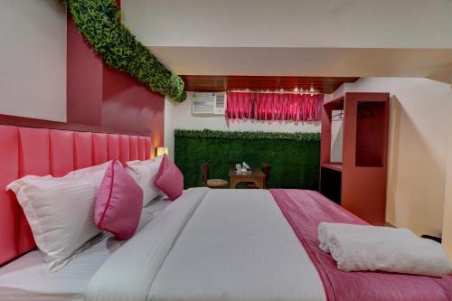 a bedroom with a large bed with pink and white pillows at Hotel Platinum Inn in Navi Mumbai