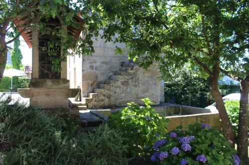 a stone fountain in a garden with flowers and trees at Casa da Eira in Marco de Canaveses