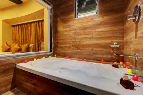 a bath tub in a bathroom with a mirror and candles at Hotel Platinum Inn in Navi Mumbai