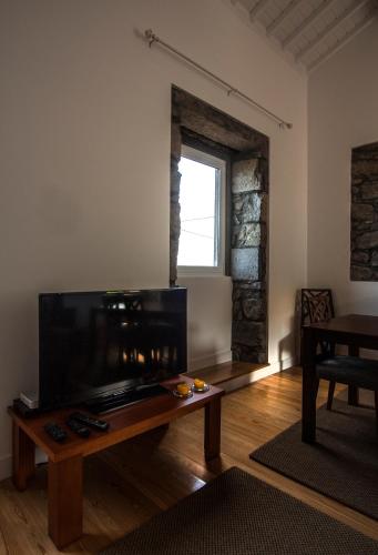 a living room with a table and a large screen tv at Casa do Simão, Açores - Now with hot tub! in Nordeste