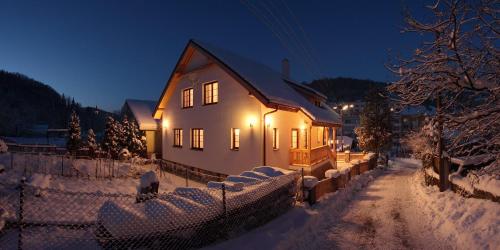 a house with lights on in the snow at night at Rekreačný dom Vyhne in Vyhne