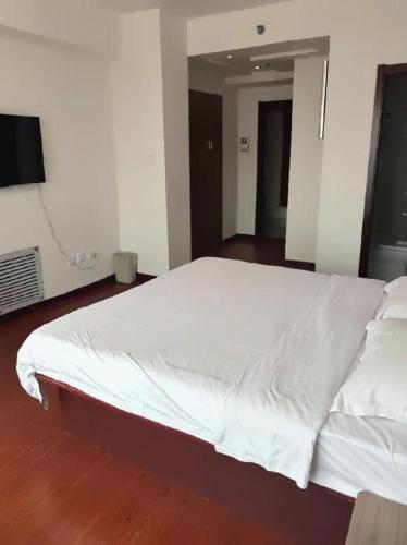 a large white bed in a room with a wooden floor at GreenTree Inn Weihai Liugongdao Wharf Qingdao North Road Express Hotel in Weihai