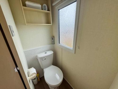 a small bathroom with a toilet and a window at TM61 3 bed CARAVAN oN THE GOLDEN PALM PET friendly in Chapel Saint Leonards