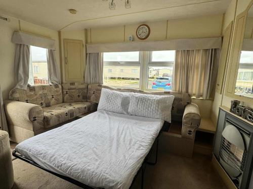 a small bedroom with a bed and a couch at TM61 3 bed CARAVAN oN THE GOLDEN PALM PET friendly in Chapel Saint Leonards