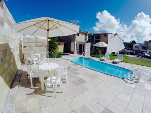 嘎林海斯港的住宿－Pousada Privê Maré Alta，一个带椅子和遮阳伞的庭院和一个游泳池