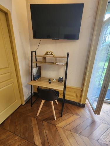 a desk in a room with a television on a wall at Le Clos Mauron Numéro 12 in Gray-la-Ville