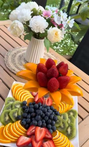 a plate of fruit on a table with a vase of flowers at The Highland Oasis in Ephrata