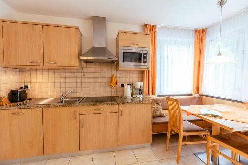 a kitchen with wooden cabinets and a table with a dining room at Haus Angelika in Nova Levante