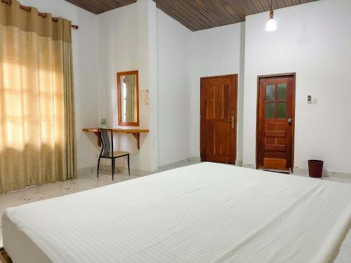 ein Schlafzimmer mit einem großen weißen Bett und einem Tisch in der Unterkunft Elepath Lodge- Pinnawala in Pinnawala