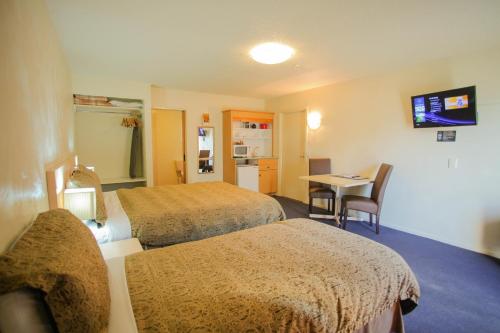 a hotel room with two beds and a table at Abbots Hamilton – Hotel and Conference Centre in Hamilton