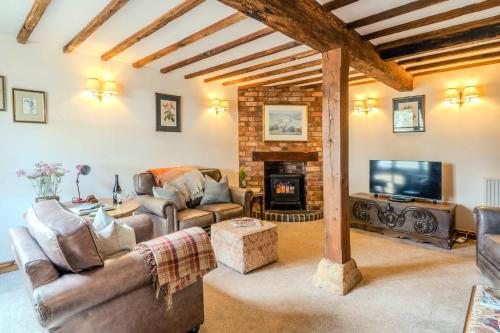 a living room with leather furniture and a fireplace at Poplar Cottage - Historic Barn in Dumbleton in Dumbleton