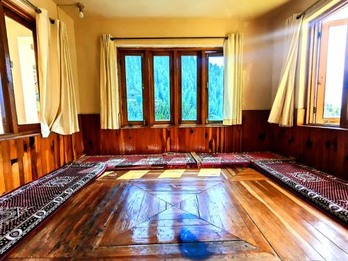 an empty room with a wooden floor and windows at Reenush Homestay in Haripūr