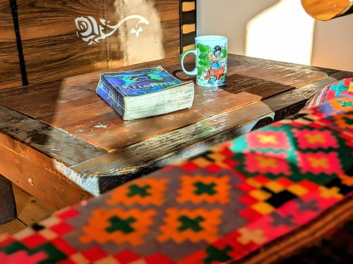 a wooden table with a coffee mug and a rug at Reenush Homestay in Haripūr