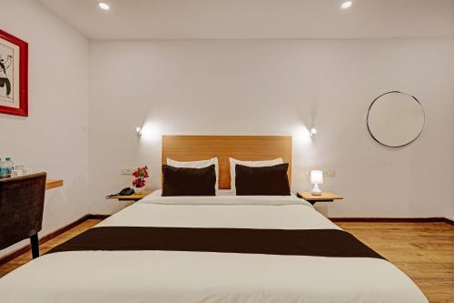 a bedroom with a large bed and a mirror at Super Townhouse Ramamurthy Nagar Formerly Navya International in Bengaluru