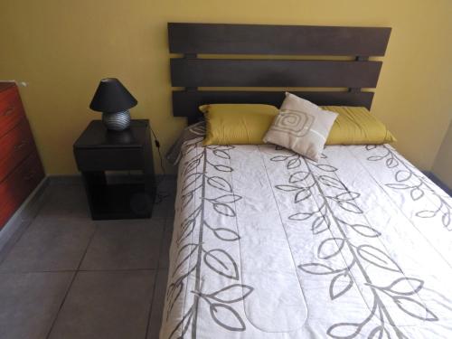 1 dormitorio con cama y mesita de noche con lámpara en Brisas Del Pacifico, en Lima
