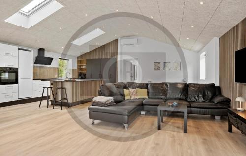 a living room with a leather couch and a kitchen at Gorgeous Home In Spøttrup With Sauna in Vester Lem