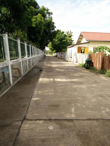 an empty street with a fence and a building at Pottery Street House in Sukhothai