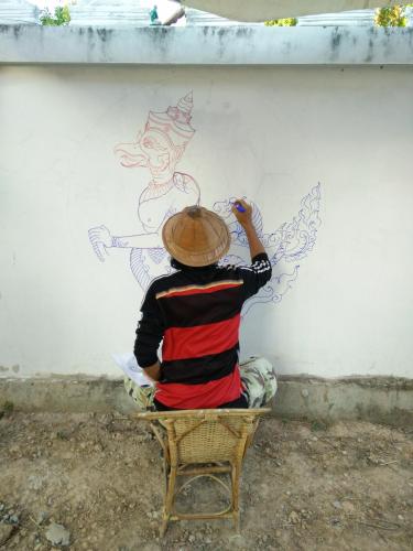 a person painting a woman on a wall at Pottery Street House in Sukhothai