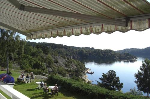 a group of people sitting at tables on a lawn near a lake at Sjøverstø Holiday in Tvedestrand